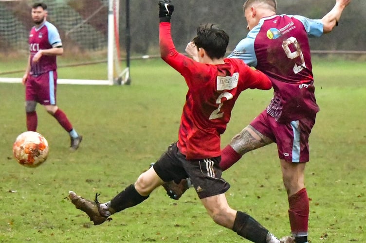 A Cwmcarn player gets a shot away despite a Crick defender's challenge