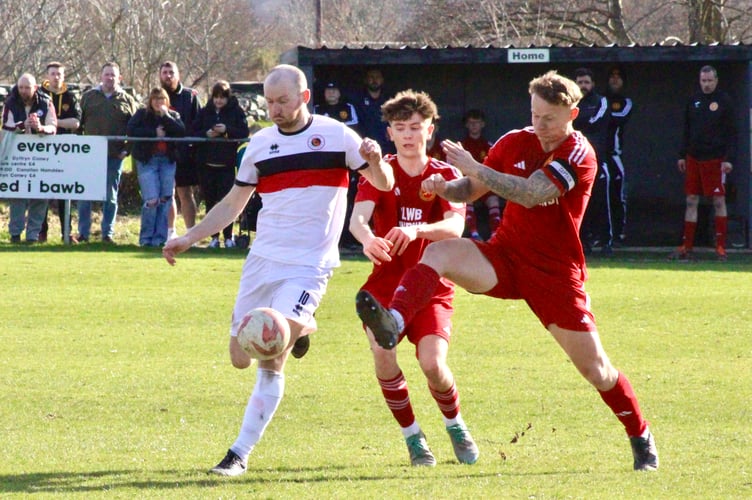 A Goytre player shields the ball under the challenge of two Llanrwst players